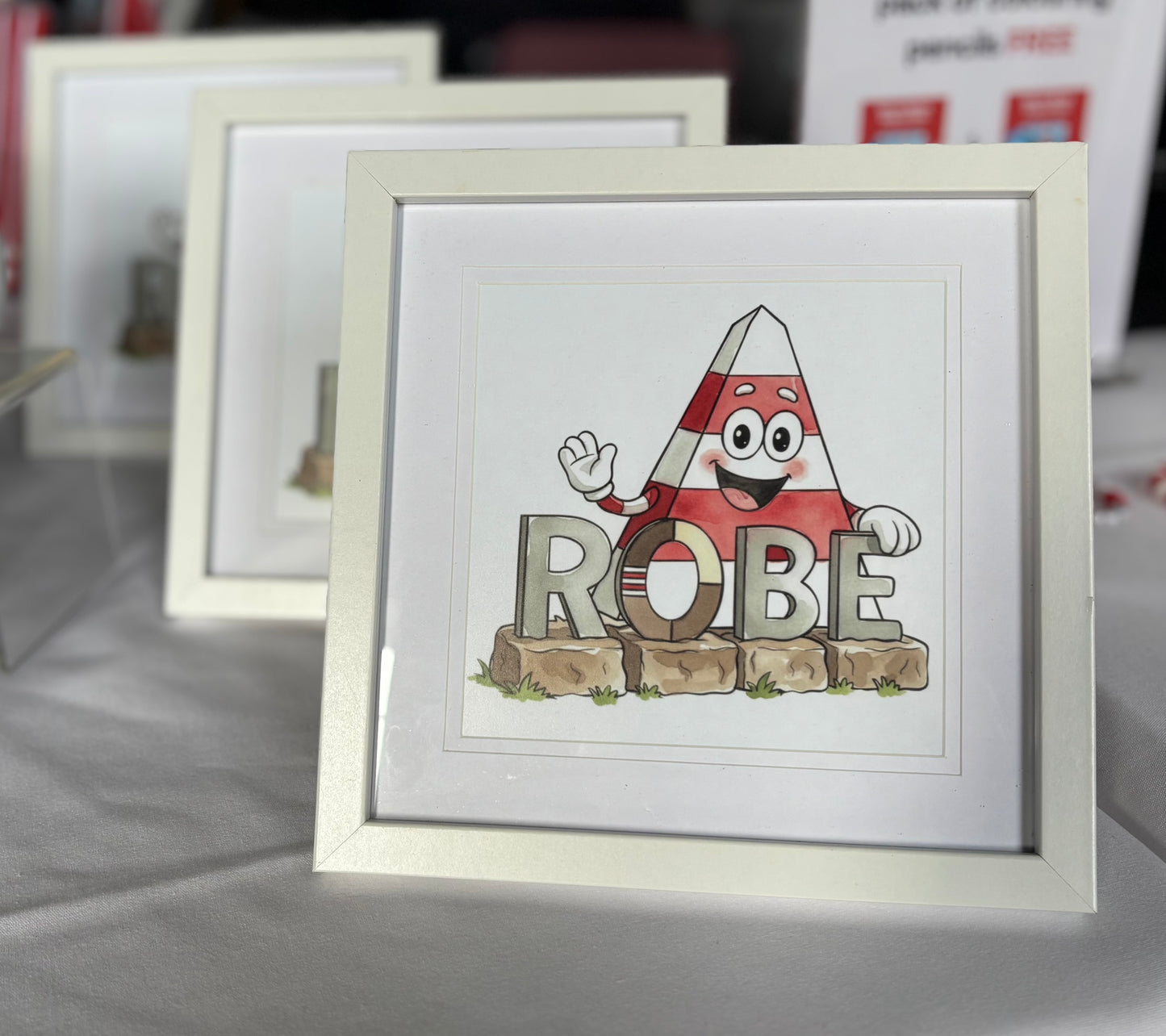 Cartoon character Obie the Obelisk with the ROBE South Australia sign print in a white frame. 